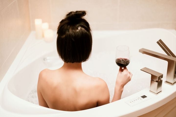 A woman relaxing in a tub with a glass of wine.